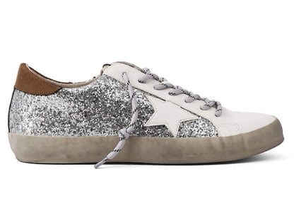 Trendy White Womens Sneakers with Silver Sparkly Sides Detailed with a White Star carved from the sparkles, a black thick line on the tongue of the shoe, and brown leather on the top of the very back of the sneaker.